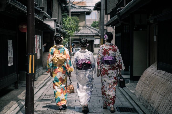 Três mulheres japonesas em trajes tradicionais passeando em uma rua