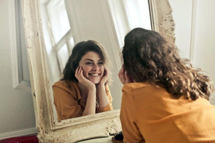 Uma mulher olhando no espelho com um sorriso positivo
