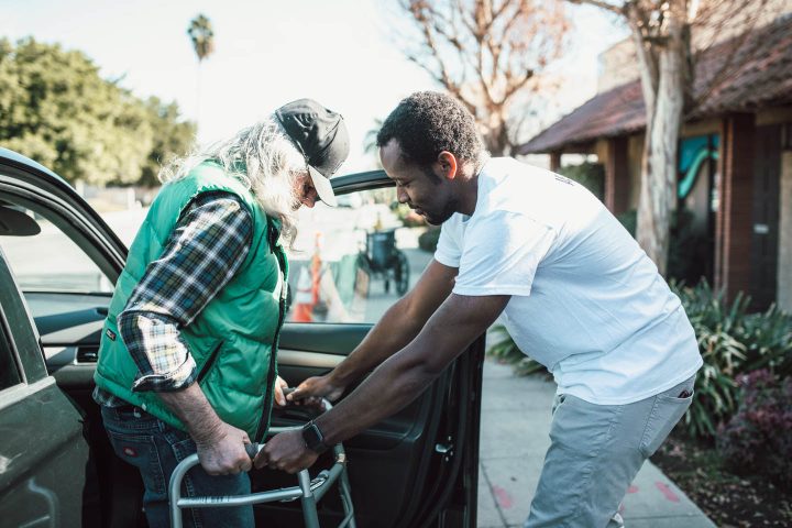 Ajudando um homem a sair do carro com um andador