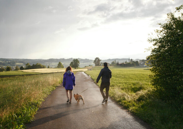 Um casal caminhando por caminho rural com um cachorro