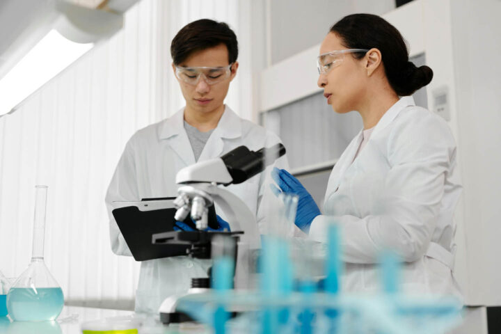 Dois pesquisadores com um microscópio discutindo as evidências