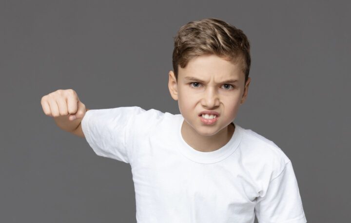 Um menino agressivo levantando o punho