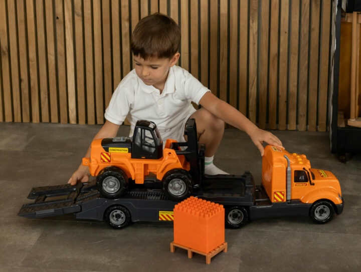 Um menino brincando com um caminhão de brinquedo