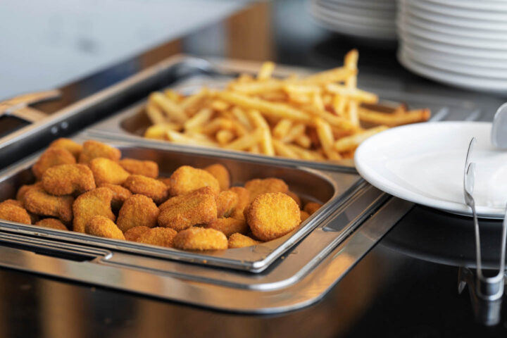 Chicken nuggets e batatas fritas sendo servidos em um balcão de comida