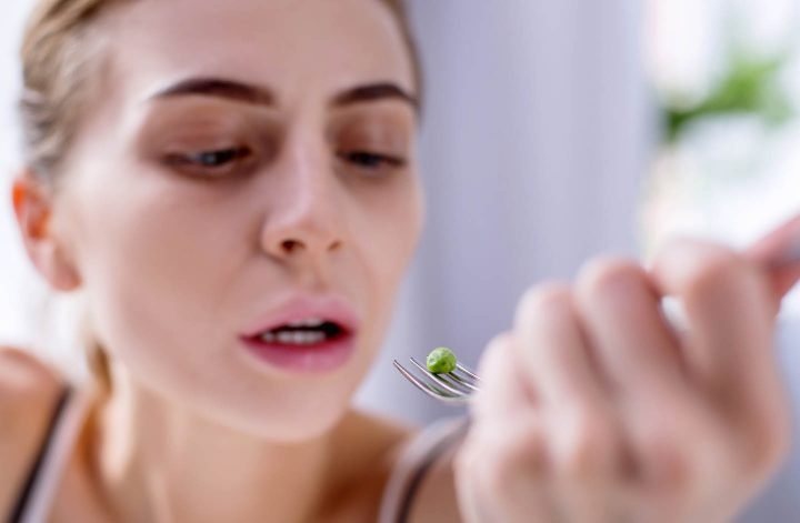 Uma garota com anorexia, angustiada por comer uma única ervilha