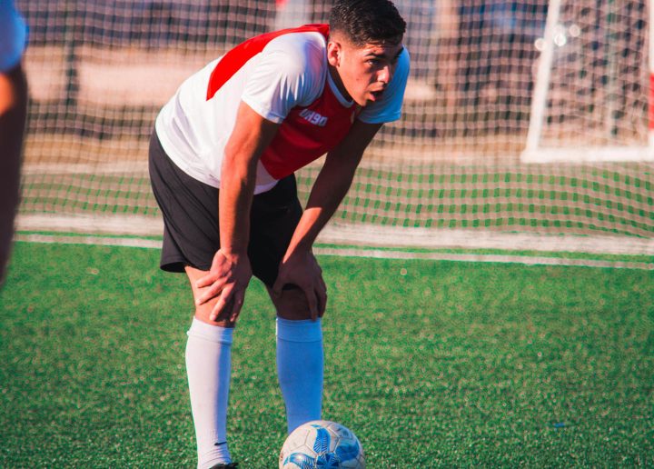 Um jogador de futebol exausto que exagera em seus níveis de exercício