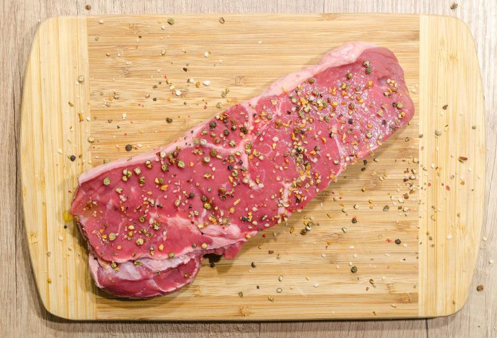 Um pedaço de carne crua em uma tábua de corte com bastante sangue