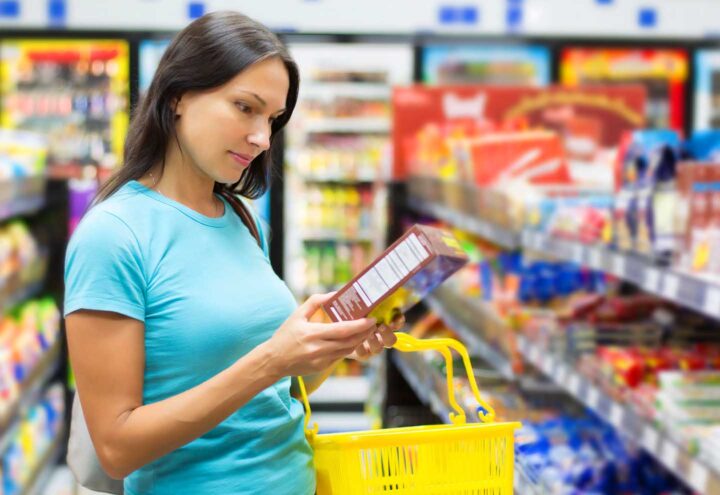 Uma mulher lendo rótulos para descobrir o conteúdo calórico de um produto no supermercado