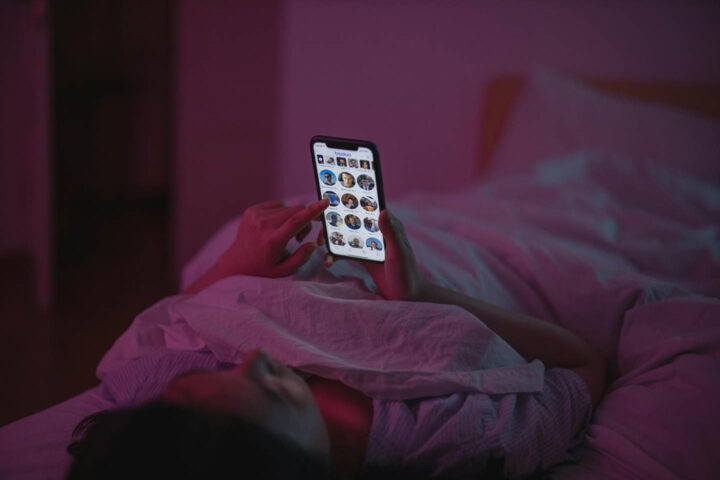 Uma mulher usando o celular na cama e perdendo o sono
