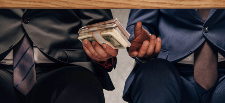 A businessman passing a bribe under the table