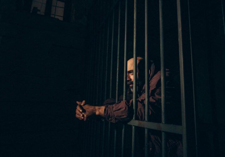 A man with a sad look inside his prison cell