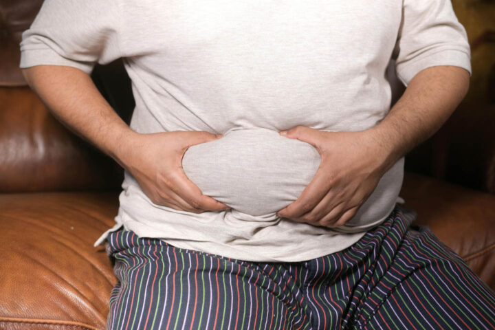 An obese man grabbing on to his belly fat