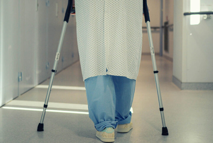 Um homem andando com muletas no hospital
