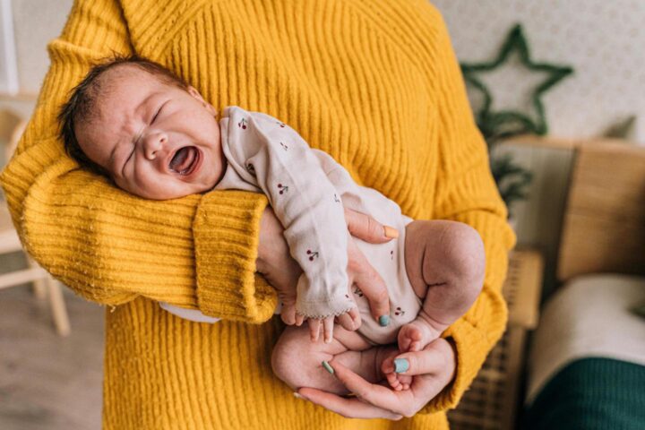 Um bebê chorando nos braços da mãe