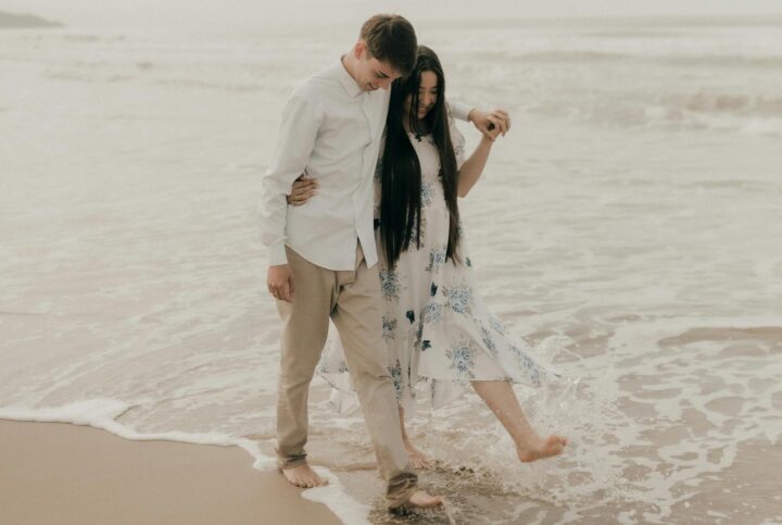 Una pareja paseando por la playa, viviendo su primer amor.