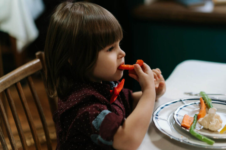 Uma menina pequena comendo vegetais