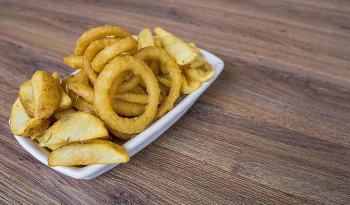 Um prato de batatas e rodelas de cebola fritas