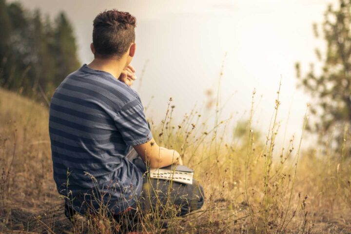 A man in nature praying and meditating on scripture
