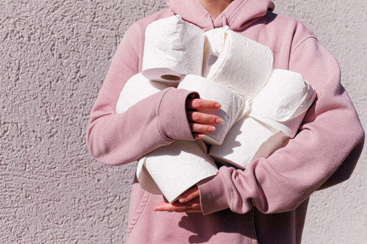 Uma mulher estocando vários rolos de papel higiênico