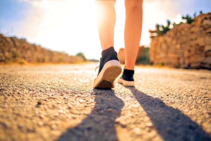 Os pés de uma pessoa caminhando ao sol